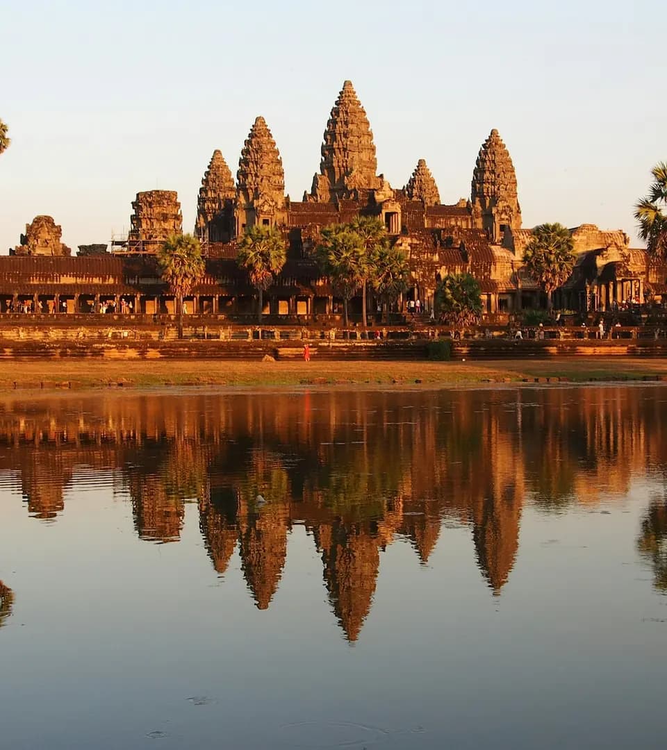 Angkor Wat at sunset, its towers reflected in the pond in front of the temple