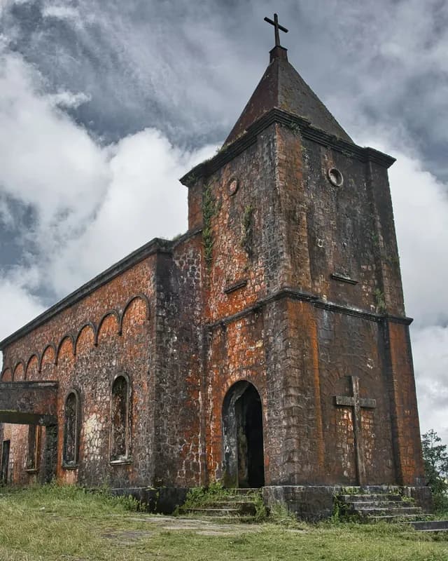 The old French-built stone church on Bokor Mountain under cloudy skies